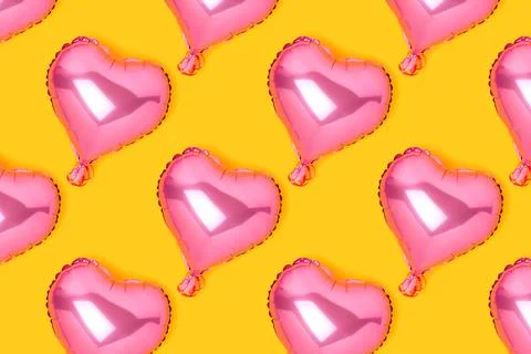 Repetitive pattern made of pink inflatable foil balloons in a heart shape. Stock Photos