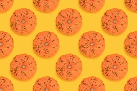 Repetitive pattern made of small orange pumpkin on a yellow background. Foto stock