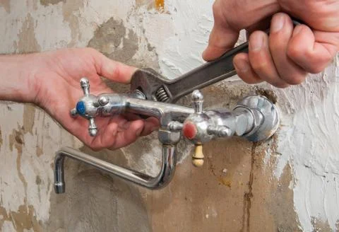 Replace an kitchen water faucet, hands plumber with adjustable wrench. Foto stock