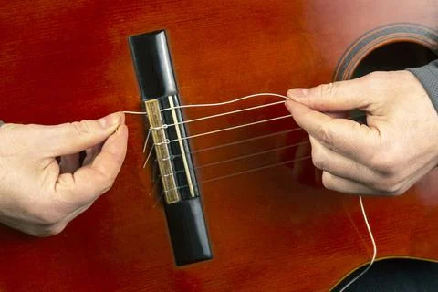 Replacement and insertion of nylon strings in a classical guitar. lesson for  Stock Photos