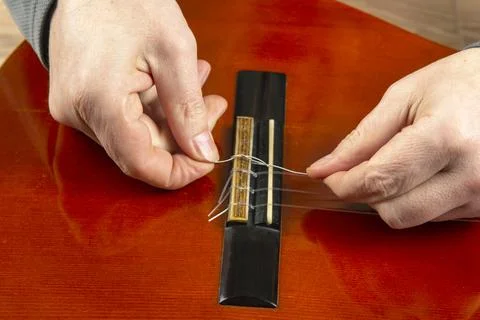 Replacement and insertion of nylon strings in a classical guitar. lesson for  Stock Photos
