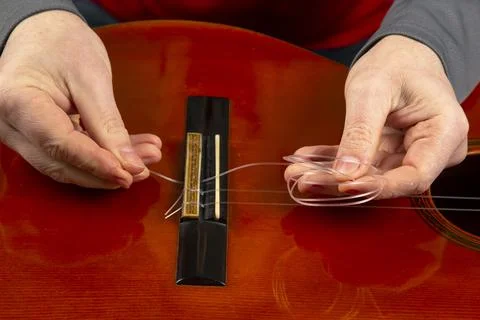 Replacement and insertion of nylon strings in a classical guitar. lesson for  Stock Photos