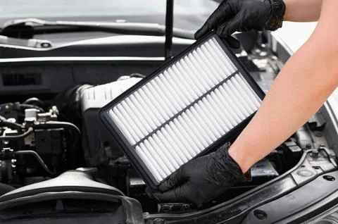 Replacing the air filter in a car. Auto mechanic in gray gloves holds an engine Foto stock