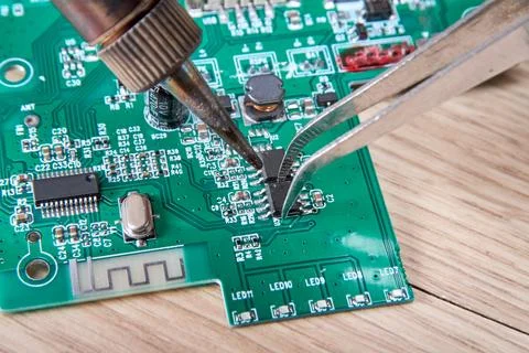 Replacing a damaged part in an electronic circuit board using a soldering iro Stock Photos