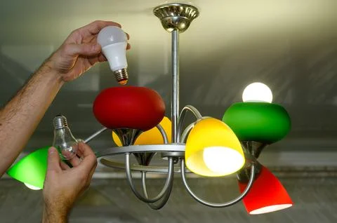 Replacing an incandescent light bulb with an LED one in a lamp. Stock Photos