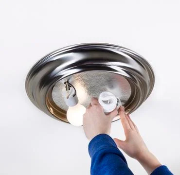 Replacing light bulb with compact fluorescent bulb Foto stock