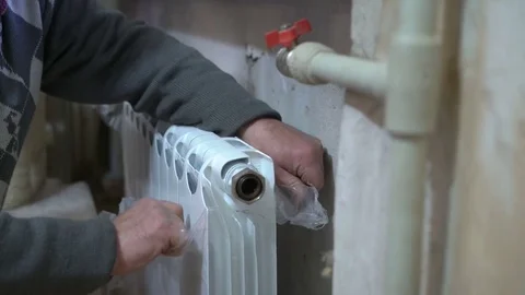 Replacing of old hot water radiator with new. Closeup of plumber hands at work. Stock Footage
