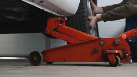 Replacing a wheel on a car raised on an orange lift at an indoor service. Stock Footage 182916252