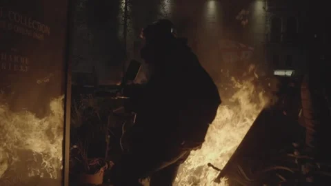 A reporter with a camera walks between a pile of burning objects at a rally. Stock Footage 298006957