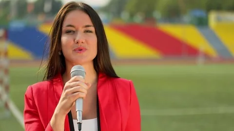 Reporter in red jacket speaks in microphone near football field Stock-Footage 276373577