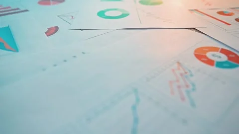 Reports and sheets with various charts and graphs are arranged on a surface, 库存影片 338303070