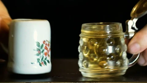 Representation of alcohol abuse, hands toasting with small mugs full of beer Stockbeeldmateriaal 96480832