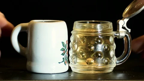 Representation of alcohol abuse, hands toasting with small mugs full of beer Stockbeeldmateriaal 98535554