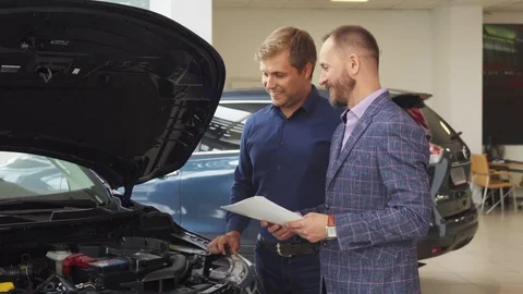 A representative man chooses new car in the car salon Stock Footage 80948609