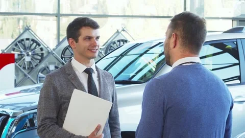 A representative seller hands over car keys to an eager buyer Stock Footage 311944768
