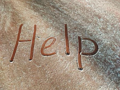 A request for help written on a dusty table Stock Photos