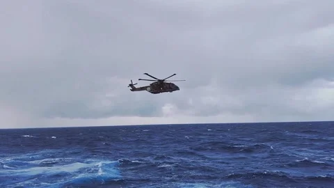 Rescue helicopter hovering low over stormy rough open sea Vídeo Stock 347687814