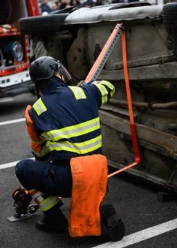 Rescue intervention man tries to secure a turned car to release the victim Stock Photos