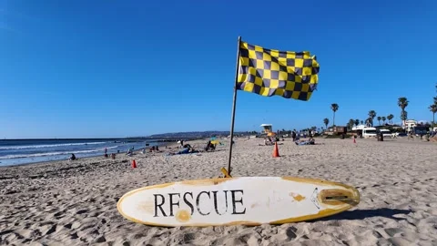 Rescue surfboard with checkered flag on sandy Ocean Beach in San Diego Stock Footage 339974424