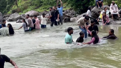 Rescue team helping people navigate a river crossing during a flood emergency Stock Footage 340251830
