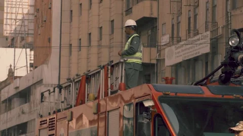 Rescue worker in helmet stands next to a ladder truck during emergency response Stock Footage 329029822