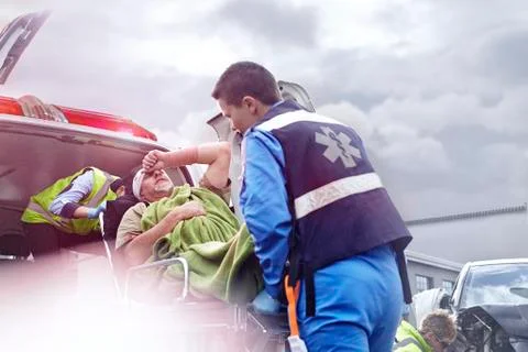 Rescue workers loading car accident victim into back of ambulance Stockfoto's