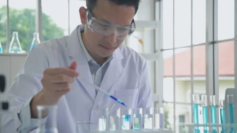 Research concept of 4k resolution. An Asian man dripping liquid into a test t Stock Footage 210228357