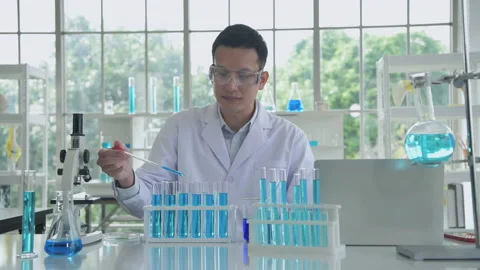Research concept of 4k resolution. An Asian man dripping liquid into a test t Stock Footage 219261870