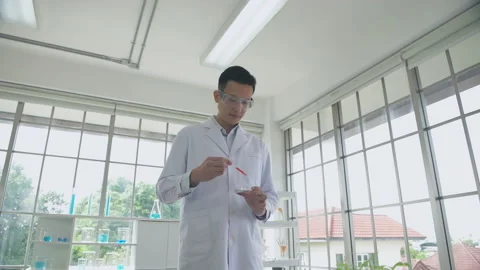 Research concept of 4k resolution. An Asian man dripping liquid into a test.. Stock Footage 231432244