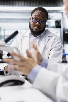 Research facility experts working together, using microscope Stock Photos
