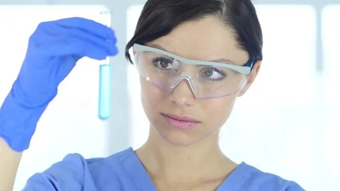 Research Scientist Looking at Blue Solution in Test Tube in Laboratory Stock Footage 81057251