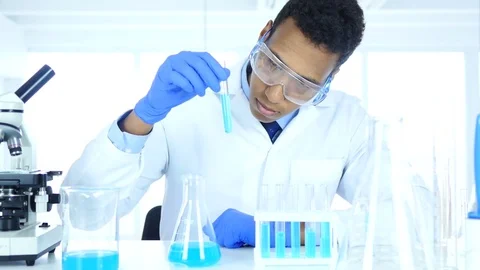 Research Scientist Looking at Blue Solution in Test Tube in Laboratory Stock Footage 81081681