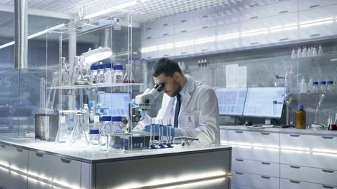 Research Scientist Looks into Microscope and Writes Down Observations.  Stock-Footage 75403365