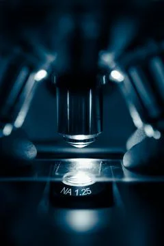 Researcher adjusting microscope under light Stock Photos