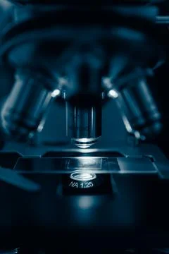 Researcher adjusting microscope under light Stock Photos