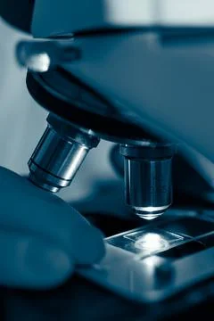 Researcher adjusting microscope under light Stock Photos