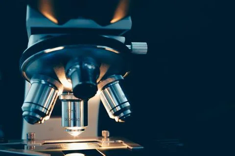 Researcher adjusting microscope under light Stock Photos