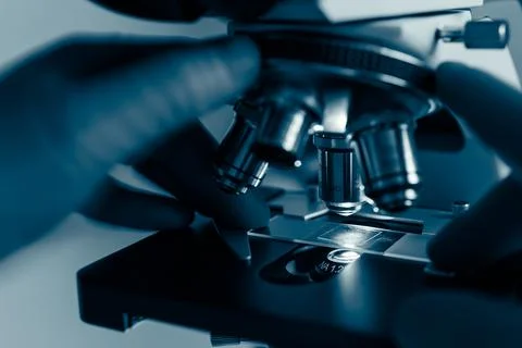 Researcher adjusting microscope under light Stock Photos