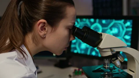 Researcher Analyzing Cells via Microscope and Computer with Man Working in Lab Stock Footage 332363269