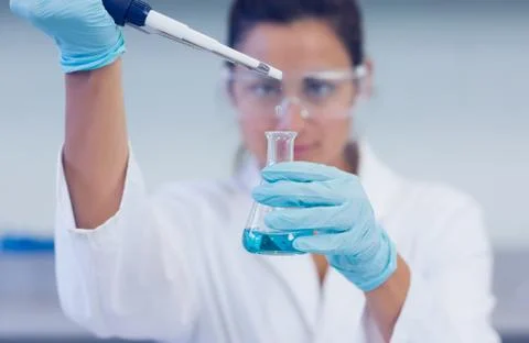 Researcher with blue liquid in flask and pipette in lab Stock Photos
