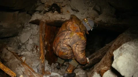 A researcher with a flashlight climbs into a collapsing mine Stock Footage 86074761