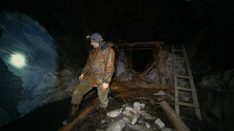 A researcher with a flashlight examines an abandoned mine with collapses Stock Footage 86074473