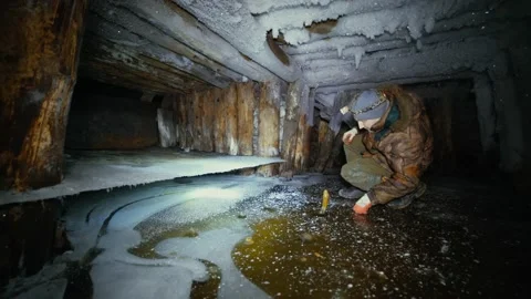 A researcher with a flashlight examines an old, icy abandoned mine Stock Footage 86074046
