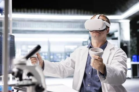 Researcher in lab workspace uses VR headset to explore three dimensional models Stock Photos