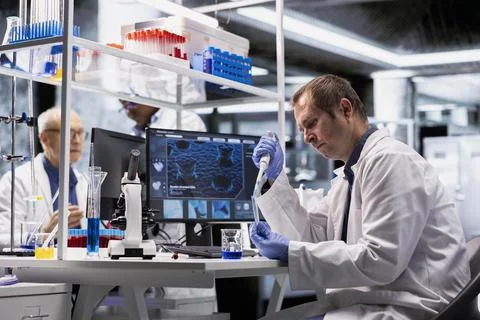 Researcher in laboratory performs experiment with pipette and jar Stockfoto's