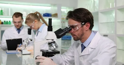 Researcher Man Examine Samples Microscope Laboratory Scientist Colleagues Talk Stock Footage 81479224