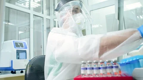 Researcher microbiologist in a protective suit puts on a protective helmet Stock-Footage 148282435