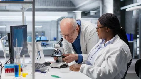 Researcher using microscope and specimen tray in laboratory workspace Foto stock