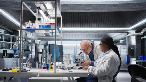 Researcher using microscope and specimen tray in laboratory workspace Stock Photos