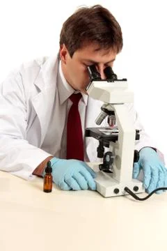 Researcher viewing substance under microscope Stock Photos